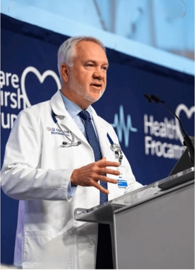 Dr. DeSarbo in white coat presenting to medical professionals